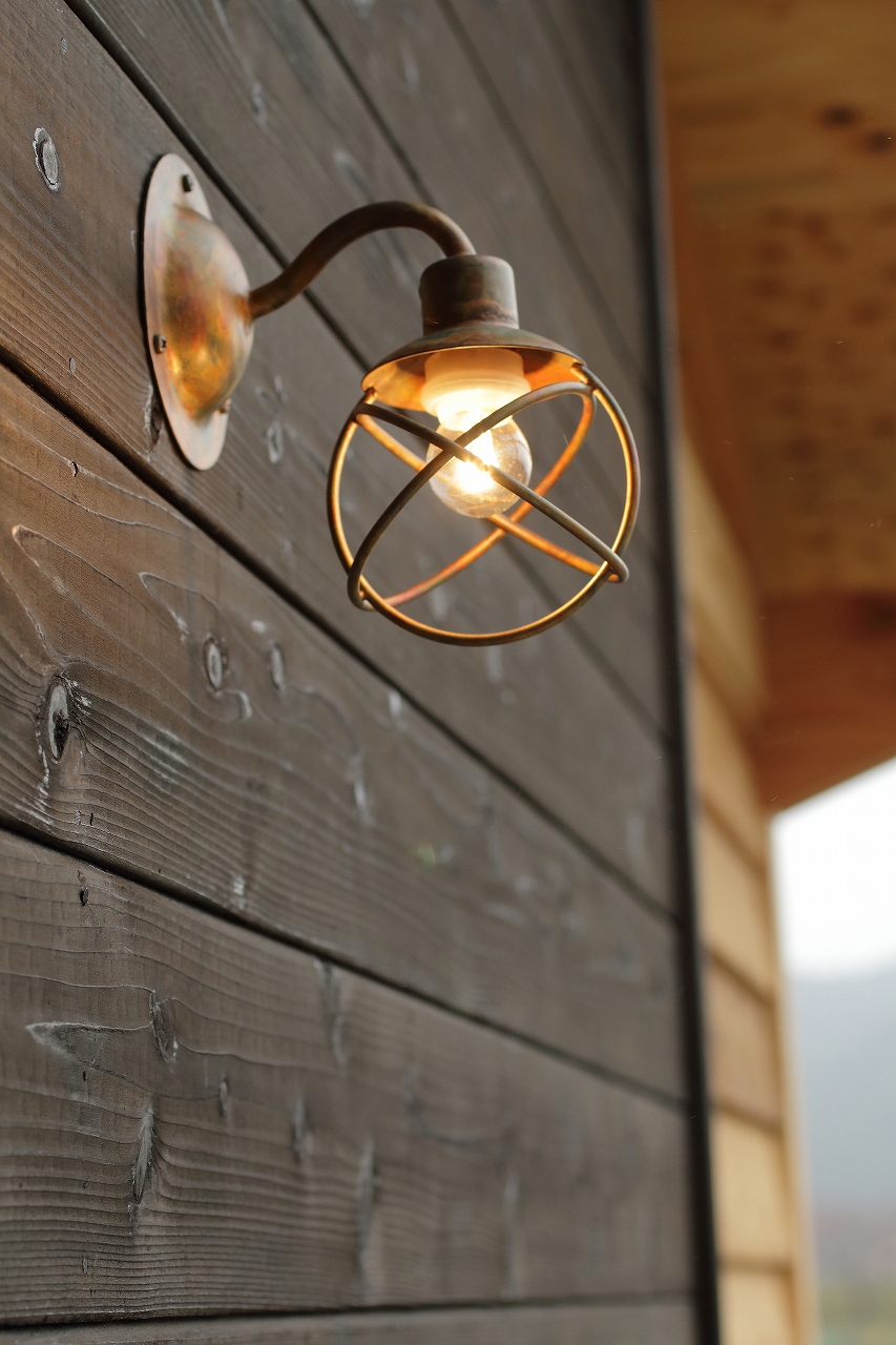 ”玄関ポーチの照明は銅製のハンドメイドの一点もの。同タイプの照明は土間スペースにも。
