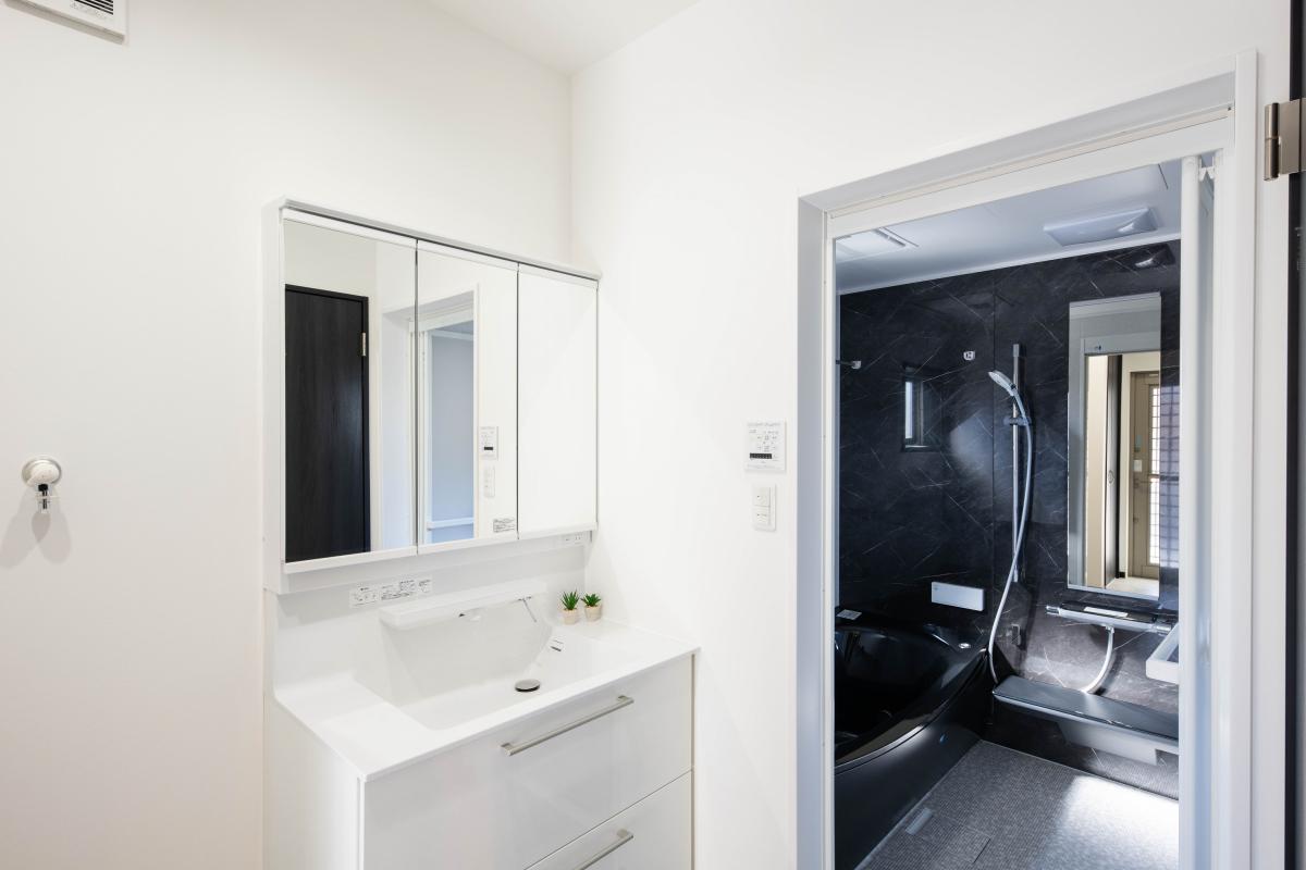 シンプルなホワイトでコーディネートされた洗面室と、高級感のあるシックなユニットバスルーム